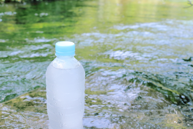 水の入ったペットボトルと涼しげな川辺